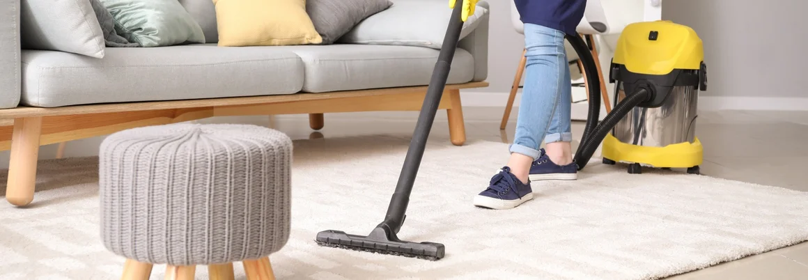 Person saugt Teppich mit Staubsauger